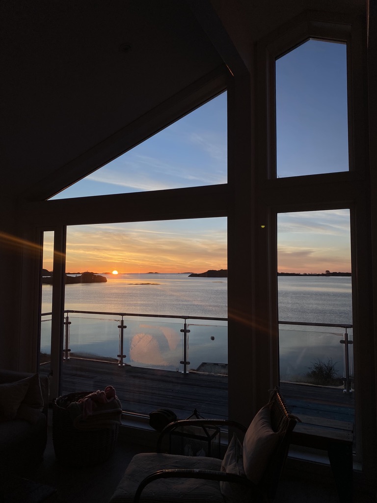 Solnedgang over havet, sett gjennom gavlvinduet på hytta